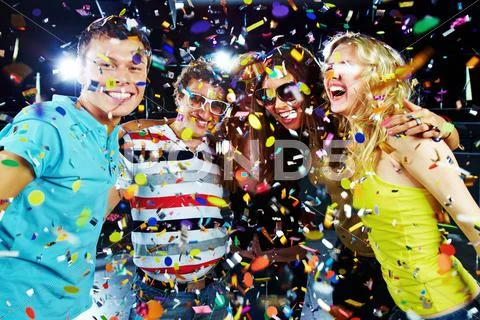 Photo of excited teenagers embracing at party under falling confetti Stock Photos