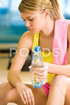 Photo of exerted female having a drink of water after difficult exercises Stock Photos