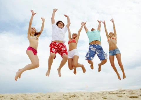 Photo of five friends in high jump over sandy beach Stock Photos