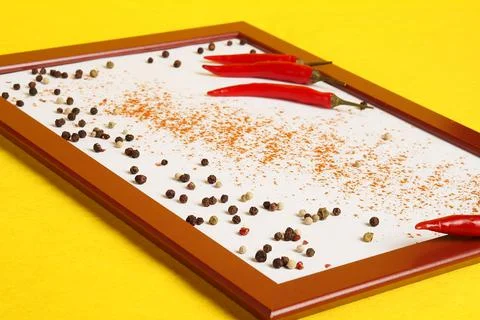 Photo frame with red chilli and spices on a yellow background. Stock Photos