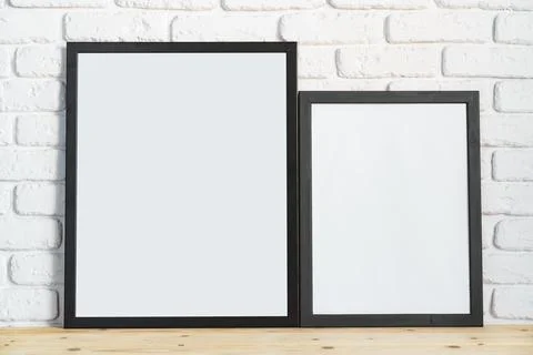 Photo frames on floor over white brick wall Stock Photos