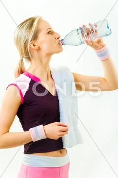 Photo of girl standing in profile and drinking water after workout on white back Stock Photos