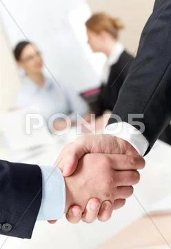 Photo of handshake of businessmen on background of communicating co-workers Stock Photos