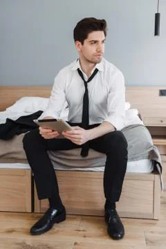 Photo of handsome brooding businessman using tablet computer while sitting on Stock Photos