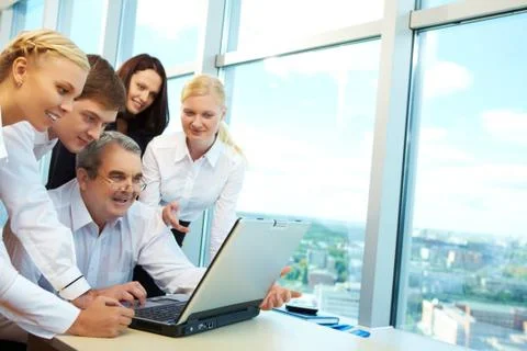 Photo of happy co-workers planning work while looking at laptop screen Stock Photos