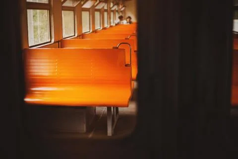 A photo of the interior of an empty retro train with orange seats on a bright Stock Photos