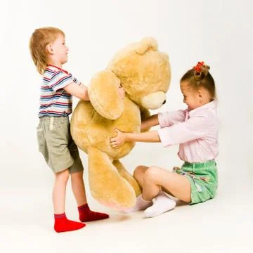 Photo of little boy and girl trying to take teddy bear from each other Stock Photos