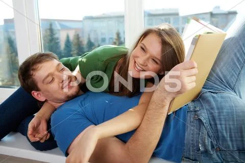 Photo of man with book and woman lying on the windowsill Stock Photos