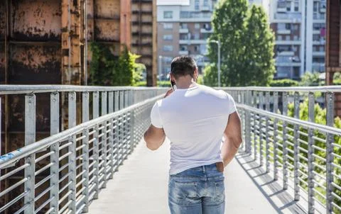 Photo of a man walking on a bridge while talking on a cell phone Stock Photos