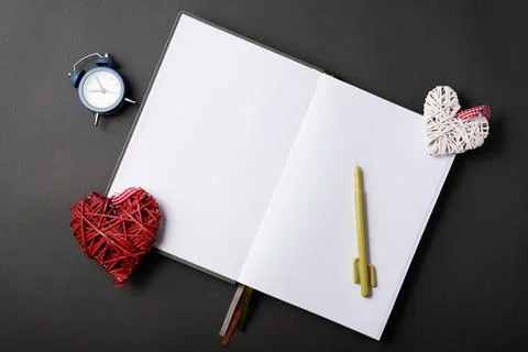Photo of open empty journal with clock and crafty hearts over black table 스톡 사진