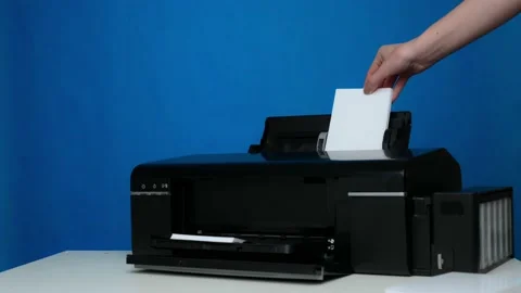 Photo printer and blank sheets of photo paper are inserted into the printer on a Stock Footage 240020139