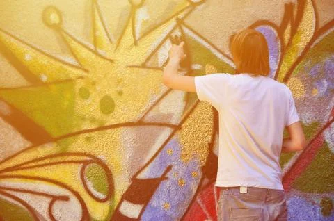 Photo in the process of drawing a graffiti pattern on an old concrete wall. Y Stock Photos