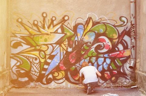Photo in the process of drawing a graffiti pattern on an old concrete wall. Y Stock Photos