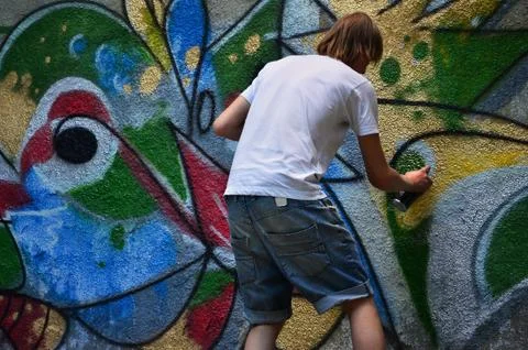 Photo in the process of drawing a graffiti pattern on an old concrete wall. Y Stock Photos