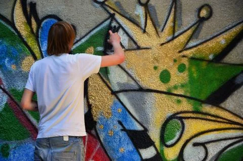 Photo in the process of drawing a graffiti pattern on an old concrete wall. Y Stock Photos