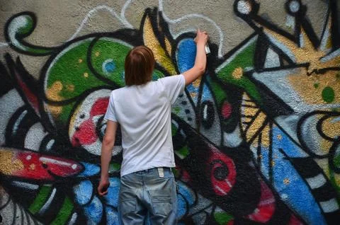 Photo in the process of drawing a graffiti pattern on an old concrete wall. Y Stock Photos