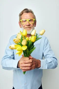 Photo of retired old man in a blue shirt with a bouquet of flowers light Stock Photos