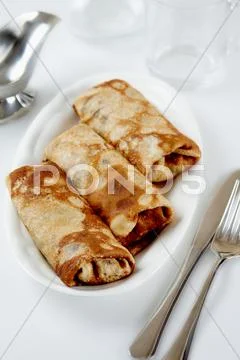 Photo of slapjacks on plate with knife, fork, glass, dishware near by Stock-Fotos