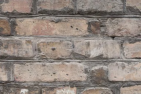 Photo of a small section of a masonry wall made of uneven bricks of red bur.. Stock Photos
