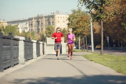 Photo of sport couple running along promenade Stock Photos