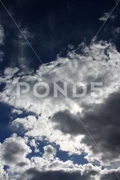 A photo of the sun shining behind clouds Stock Photos