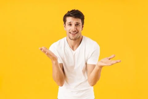 Photo of surprised man in basic t-shirt smiling at camera and throwing up arm Stock-Fotos