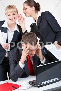 Photo of thinking boss in front of laptop while one of his employees whispering Stock Photos