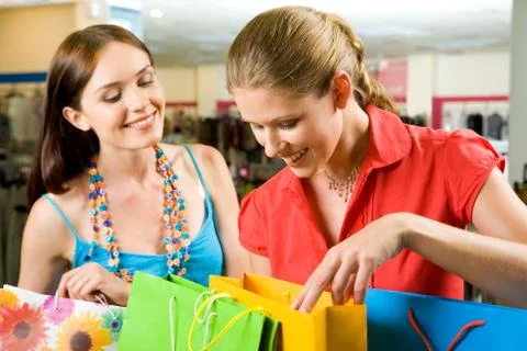 Photo of two friends looking through their shoppings with smiles in the mall Stock Photos