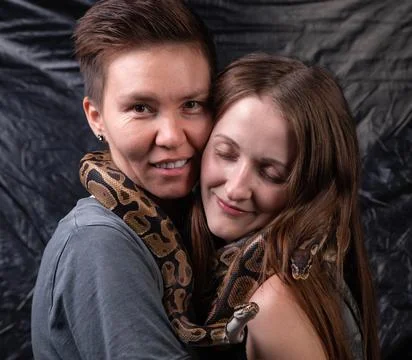 Photo of two happy women with python on neck Stock Photos