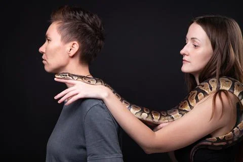 Photo of two women with python on shoulders in profile 写真素材