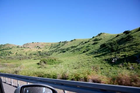 Photo from the window of a car driving on the highway. Landscape of a green p Stock Photos