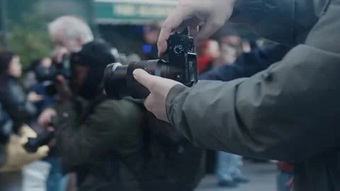 Photographer adjusting camera settings during public event Stock Footage 305354544