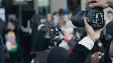 Photographer adjusting camera settings during public event Stock Footage 306461582