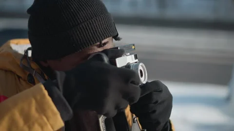Photographer adjusting lens while walking on snowy urban path Video stock 318626980
