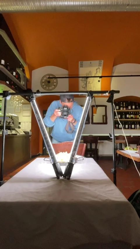 Photographer adjusting reflector and led lights over tabletop dish in small Видео 344586470