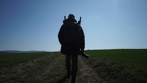 A photographer with a backpack on his shoulders walks along a dirt road Stock Footage 126358853