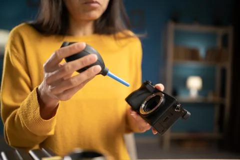 Photographer blowing dust off camera sensor matrix using air blower Stock Photos