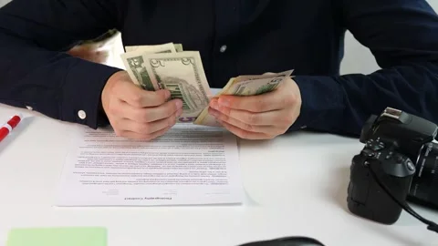 A photographer with a camera and a contract counts the money received for the Stock-Footage 312732514