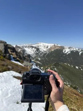 Photographer capturing mountain scenery with camera Fotos de archivo