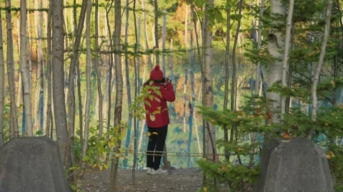Photographer capturing the reflection of an autumn forest in Hokkaido Stockbeeldmateriaal 344580582