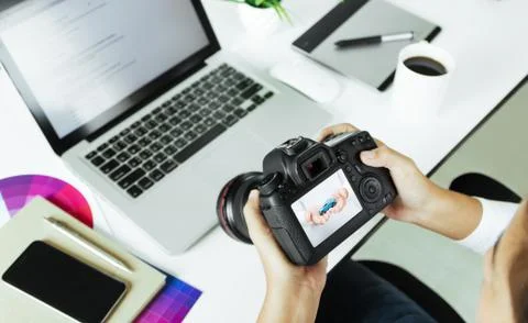 Photographer checking camera device on desk Stock Photos