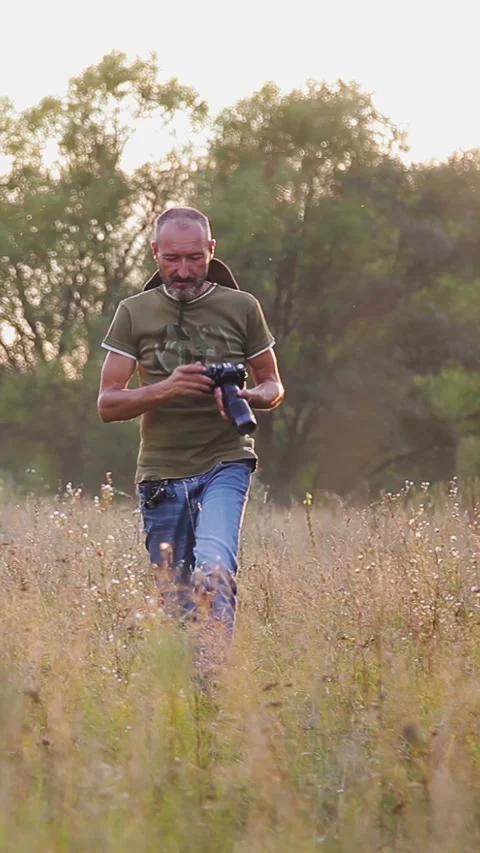 Photographer doing his work in the evening sunshine. Vertical video. Video stock 305024014