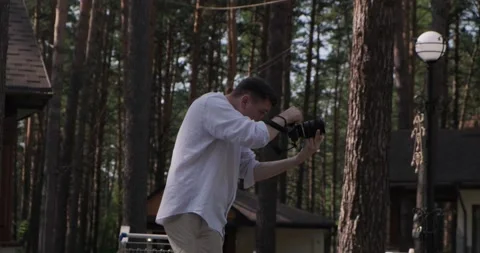 Photographer guy shoots against the backdrop of nature on a professional camera Stock Footage 221704201