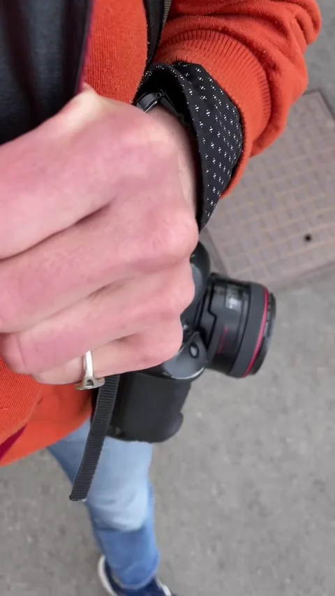 Photographer holding camera strap with visible ring during city walk Stock Footage 335355766