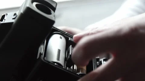 Photographer loading medium format film into camera back Stock Footage 293464582