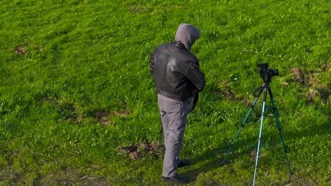 Photographer Man Setting Up A Camera Tripod In The Grass Field Stock Footage 265440429