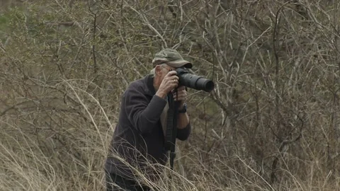 Photographer in marsh with camera and long lens, 2k Stock Footage 153699170