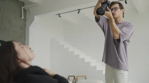 Photographer photographs model from an upper angle in bright studio in natural Stock Footage 243458077