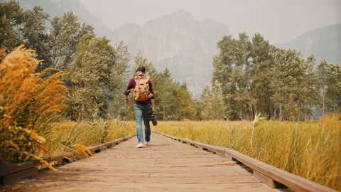 Photographer with professional camera set walking through autumn Yosemite Park Stock Footage 138279801