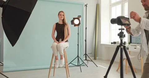 Photographer shooting model in studio with lights, camera, and seamless backdrop Stock Footage 343249847
